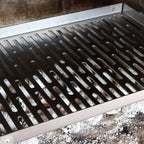 Stainless steel braai grid with visible coals underneath