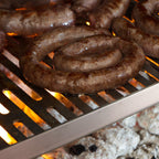 Sausages cooking on a grill with flames below